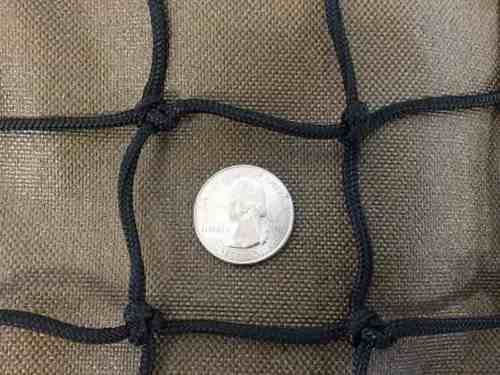A quarter sits inside 1 3/4" slow feed hay net mesh to show how large the openings are.