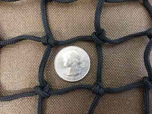 A quarter sits inside 1 1/4" slow feed hay net mesh to show how large the openings are.