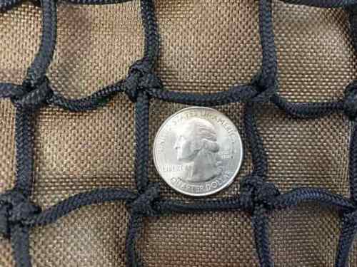 A quarter sits inside 1" slow feed hay net mesh to show how large the openings are.