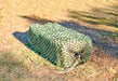 West coast size hay bale net for slow feeding horses filled with a large bale of grass hay and laying on the ground.